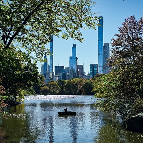 A person sitting in a small boat in the Reservoir of Central Park